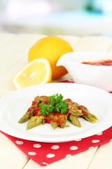 Asparagus on plate, on wooden table on bright background