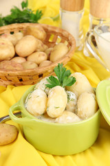 Tender young potatoes with sour cream and herbs in pan