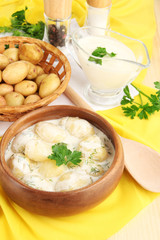 Tender young potatoes with sour cream and herbs in wooden bowl