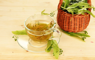 Glass cup of tea with linden on wooden table close-up