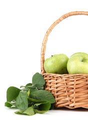 Juicy green apples with leaves in basket, isolated on white