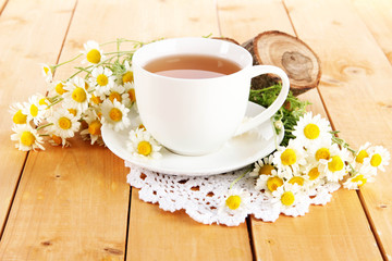 Cup of chamomile tea and chamomile on wooden table