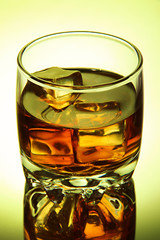 Brandy glass with ice on green background