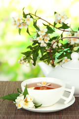 Cup of tea with jasmine, on bamboo mat, on bright background