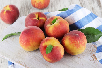 Peaches on board on napkin on table on wooden background