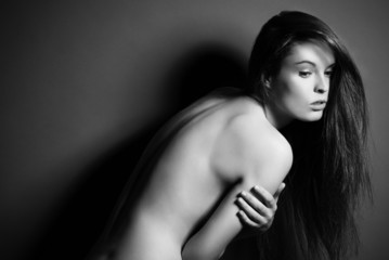 Posing brunette woman with long hair on gray