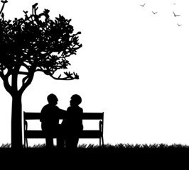 Lovely retired elderly couple sitting on bench in park