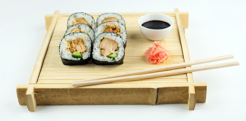 Chicken maki rolls with soy sauce on a rustic bamboo mat