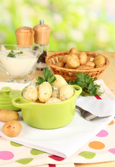 Tender young potatoes with sour cream and herbs in pan