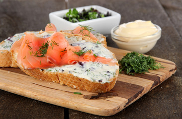 Fish sandwiches on cutting board on wooden table