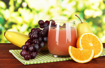 Glass of fresh juice on table on bright background