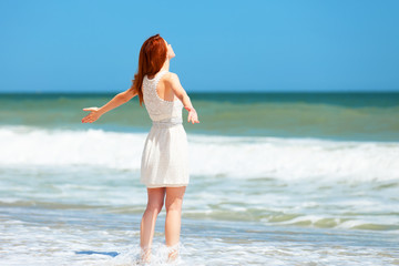 Fototapeta na wymiar Redhead girl on the beach in spring time.