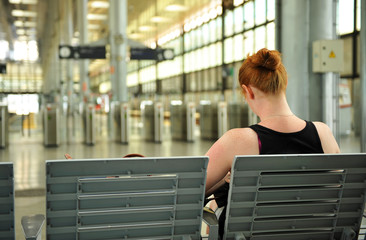 Mujer pelirroja sentada en la estación esperando