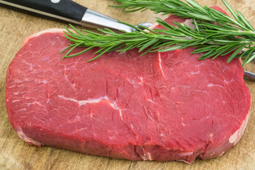 frisches Rumpsteak mit Rosmarin und Fleischgabel auf Holz