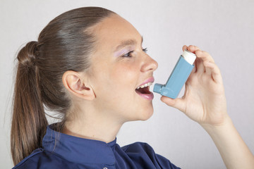 Obraz premium Cute smiling nurse showing, using an asthma inhaler