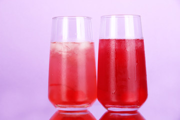 Two cherry cocktails with ice on purple background