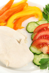 Boiled chicken breast on plate with vegetables close up