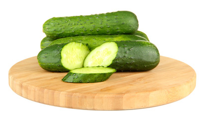 Tasty green cucumbers on wooden cutting board, isolated on