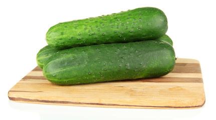 Tasty green cucumbers on wooden cutting board, isolated on