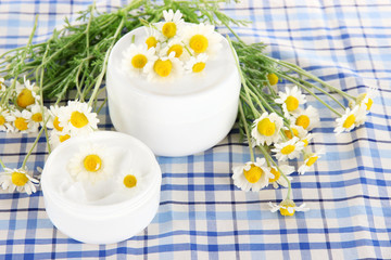 Cream with chamomile on checkered cloth background
