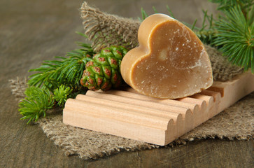 Hand-made soap and green pine cones on wooden background