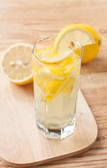 Lemon drink in a glass and lemons on a wooden surface