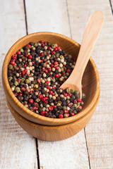Mixed pepper in wooden can on wooden background