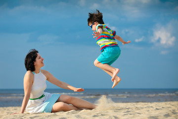 Young mother and son having fun on the beach