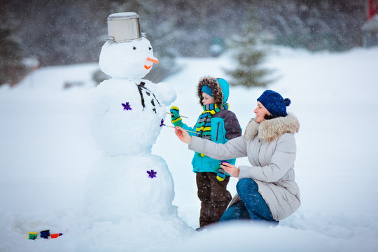 Little boy with his mother painting a snowman