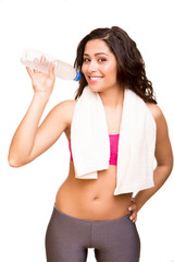Attractive fitness woman posing with gym towel holding a bottle