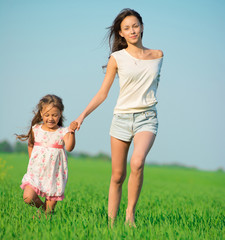 Young happy girls running at green wheat field