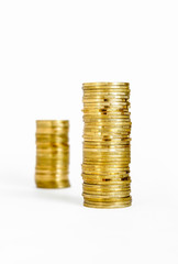 Two piles of coins, one blurred in the background, isolated on white background