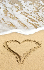heart outline on the wet beach sand against sea wave
