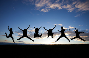 silhouette of kids jumping in sunset