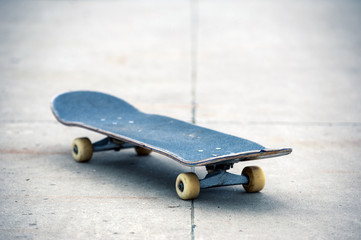 Old used skateboard isolated on the ground. Shallow dof.