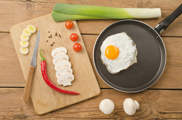 Fried egg in a frying pan on a wooden background