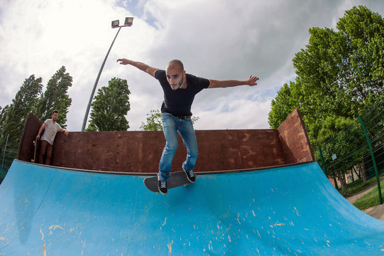 Skateboarder Doing A Skateboard Trick In Halfpipe At Skatepark.