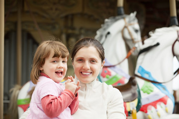 mother with  girl against carousel