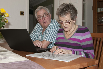 Elderly couple solving crossword puzzle