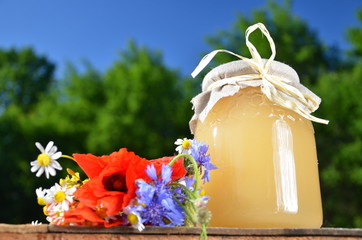 polne kwiaty i słoik pełen smacznego miodu na tle nieba © Darios