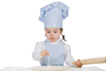 Beautiful little girl cooking  and sprinkle with flour pizza