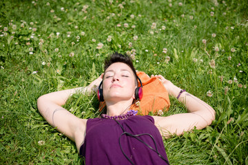 beautiful hipster short hair woman listening music in the park