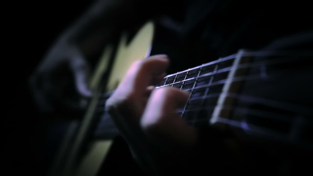 Fingers playing chords of a guitar