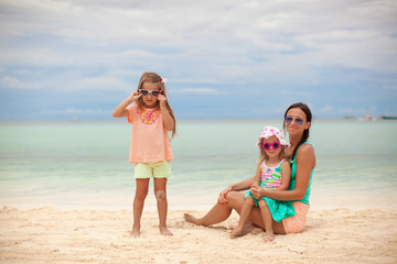 Fototapeta na wymiar Bright mother and two her kids at exotic beach on sunny day