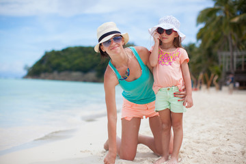 Young mother and her little daughter in hats have fun on beach