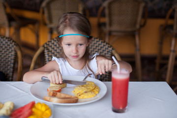 Adorable little girl having breakfast at resort restaurant