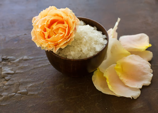 Sea salt in bowl with rose on wooden background