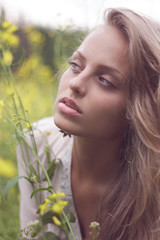 Fototapeta premium Portrait of a sexy blond girl in a field of yellow flowers