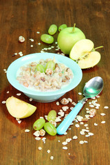 Useful oatmeal in bowl with fruit on wooden table close-up