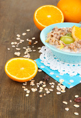 Useful oatmeal in bowl with fruit on wooden table close-up